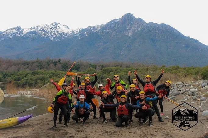 Equipo Ñuble Rafting posando junto al río con montañas nevadas